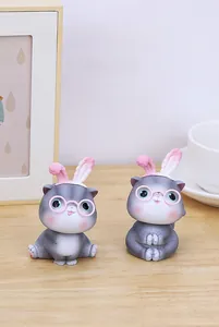 Detail of gray nodding cats with pink rabbit ears and glasses on a wooden desk