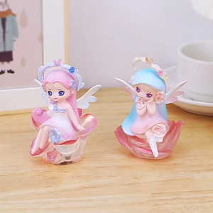 Detailed view of pink and blue fairy figurines on rose petal bases for desk decor