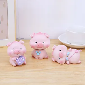 Gros plan de trois figurines de cochons roses mignons en résine sur un bureau