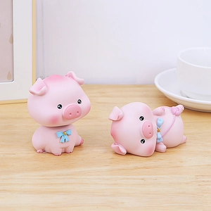 Figurines de cochons mignons en résine rose avec étoiles dorées sur bureau en bois