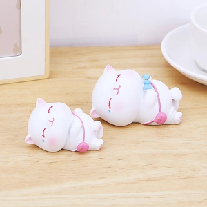 Gros plan de figurines de chats endormis en résine avec détails roses sur bois