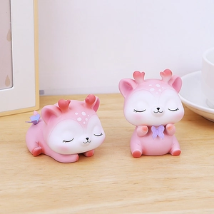 Détail de figurines cerf en résine rose avec bois en cœur rouge sur bureau en bois
