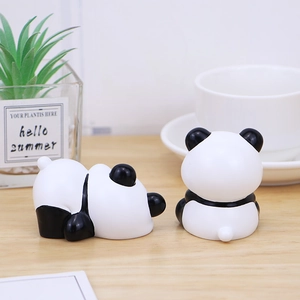 Cute panda resin figurines on wooden desk with green plant for home office decor