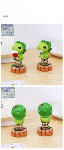 Macro detail of cute frog resin car ornaments on wood bases with spring shaking heads
