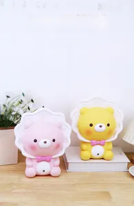 Detail of pink and yellow cartoon bear money boxes on a wooden table with home decor