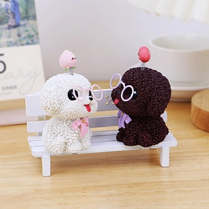Lindas figuras de perro teddy de resina con resortes sobre un pequeño banco blanco de madera