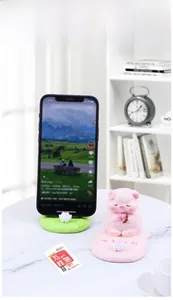 Detail of pink pig phone stand with lotus base on marble table for office desk decor