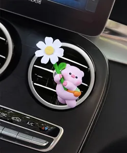 Close-up of a cute pink pig figurine with a white daisy on a car air vent outlet
