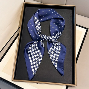 Elegant navy houndstooth print silk square scarf tied in a bow on a display stand