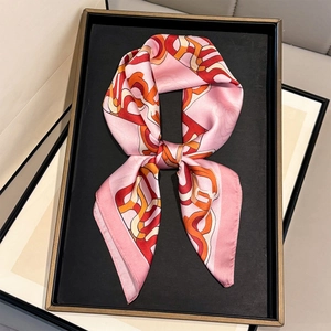 Detail of pink silk square scarf with geometric chain and rose print on a black tray