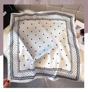 Detail of silk scarf with black polka dots and ornate border on a stylish background