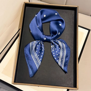 Close-up of a navy blue polka dot silk scarf tied as a bow in a golden frame display