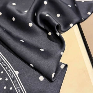 Detail of silk scarf showing black and white polka dot pattern and satin texture