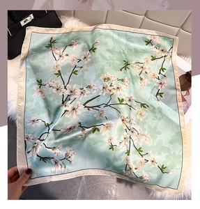 Detail of mint green floral silk scarf with magnolia prints on soft white plush background