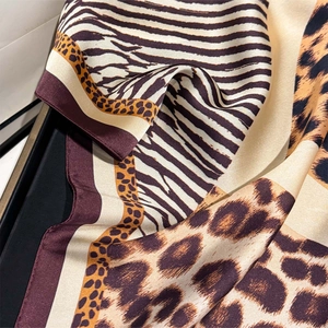 Detail of leopard and zebra print silk scarf with burgundy hem and smooth texture