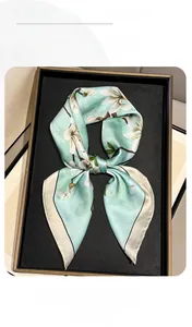 Detail of mint green silk scarf with white magnolia print in a premium gift box