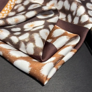 Detail of leopard print silk scarf showing glossy texture and high-quality hemmed edges