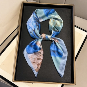 Floral print silk scarf tied in a bow featuring blue hydrangea patterns on cream background