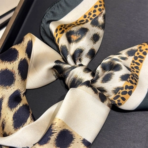 Macro shot of silk leopard print scarf showing detailed satin texture and classic pattern
