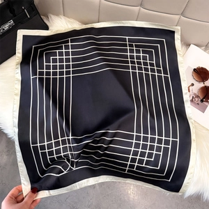 Detail of black and white geometric silk scarf on soft fur rug with luxury accessories
