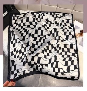 Detailed view of silk-like square scarf with black and white wavy geometric print texture
