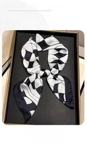 Detail view of silk scarf featuring black and white geometric houndstooth pattern and satin sheen
