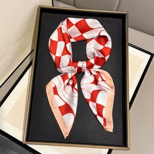 Elegant red and white geometric silk scarf folded in a bow shape on a black tray