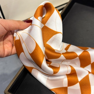 Detail of soft silk-feel square scarf with geometric orange checkerboard pattern