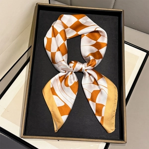Silk-textured square scarf with orange and white geometric check pattern on display