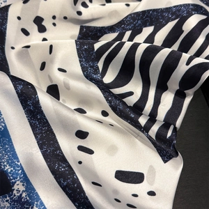 Macro shot of silk scarf showing geometric patterns and premium satin fabric texture