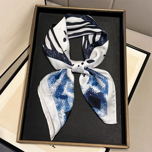 Close-up of a blue and white geometric print silk scarf tied in a bow on a black tray