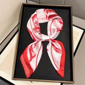Detail of red and white shell print silk scarf tied in a flat knot on a display tray