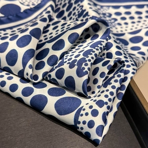 Dettaglio ravvicinato di sciarpa in seta a pois blu con elegante finitura lucida