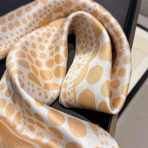 Dettaglio di sciarpa in seta con pois dorati artistici e trama in raso liscio