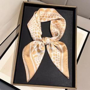 Dettaglio di un foulard in seta dorato a pois con motivi irregolari e bordi ondulati