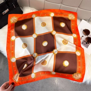 Close-up of square silk scarf with orange borders and golden lion print on fur rug