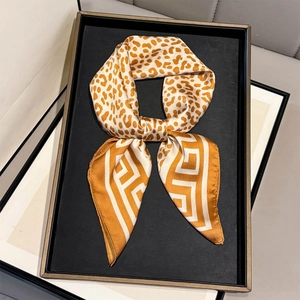 Elegant silk scarf featuring leopard print and geometric patterns on a display tray
