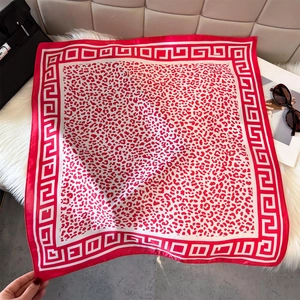 Red and white leopard print silk scarf with Greek key pattern on plush background