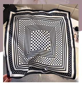 Flat lay of black and white polka dot silk scarf with stripes on plush background