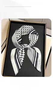 Vue détaillée d'un foulard en soie noir et blanc à pois et rayures dans son coffret