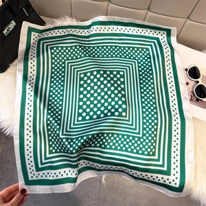 Close-up of green and white printed silk scarf on fur rug with fashion accessories