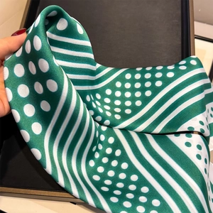 Detail of green and white polka dot silk scarf with elegant twill texture and stripes