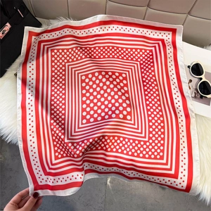 Close-up of red and white polka dot silk scarf draped over a black handbag