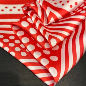 Close-up of red and white polka dot silk scarf with elegant striped texture detail