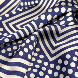 Macro shot of silk scarf showing navy and cream stripes with polka dots and soft luster