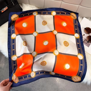 Elegant silk square scarf with orange chain print and navy border on plush background