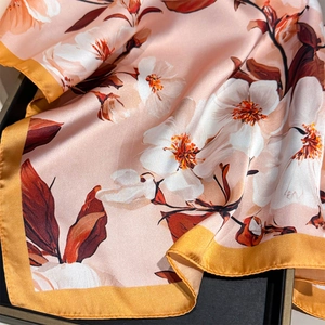 Detailed close-up of camellia floral print silk scarf with golden yellow edges