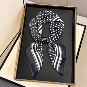 Détail d'un foulard en soie montrant des motifs à pois et à rayures monochromes