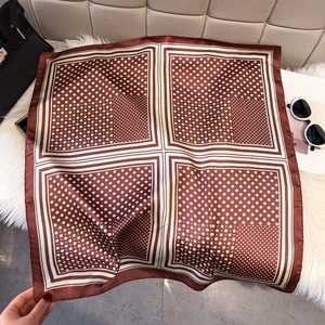 Gros plan d'un foulard carré marron à pois sur fausse fourrure blanche avec accessoires