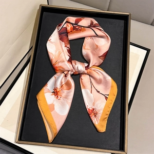 Detailed view of peach pink silk scarf with floral prints and orange stitched edges